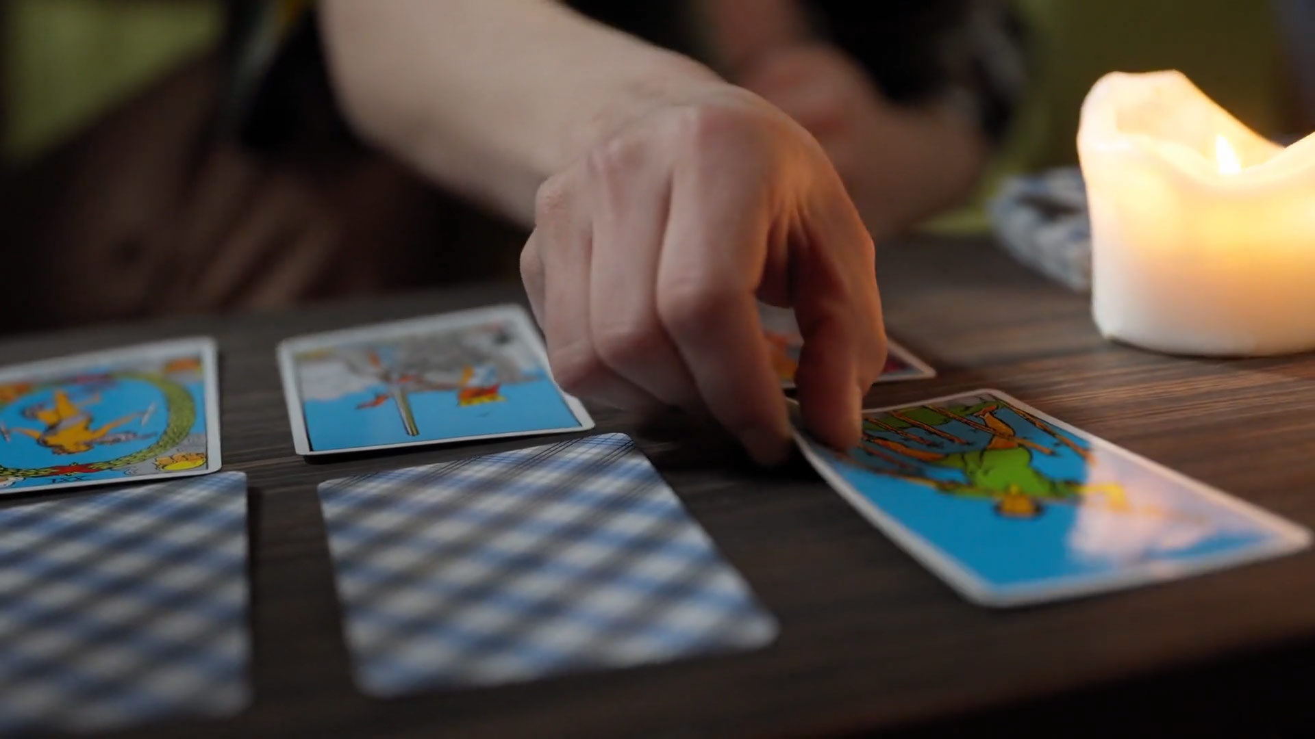 a hand turning over a tarot card showing the 6 of Wands